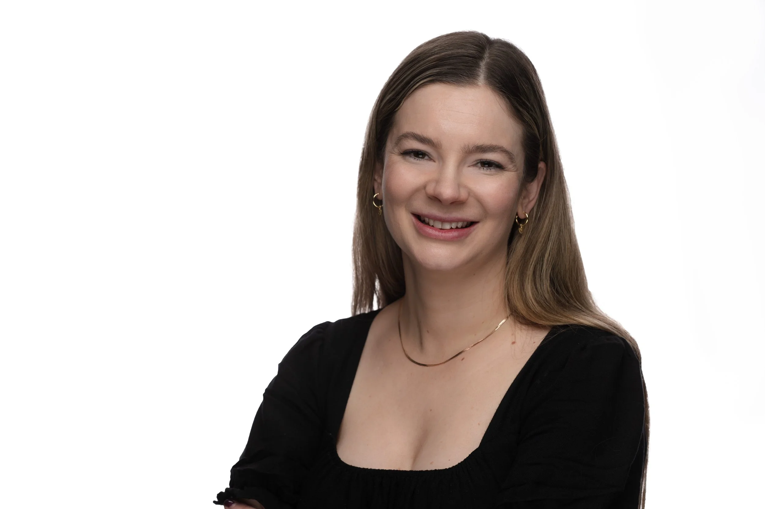 Mercedes Mercier, crime fiction author and writing mentor at Hey Author. A woman with brown hair and earrings smiling, wearing a black top, against a plain white background.