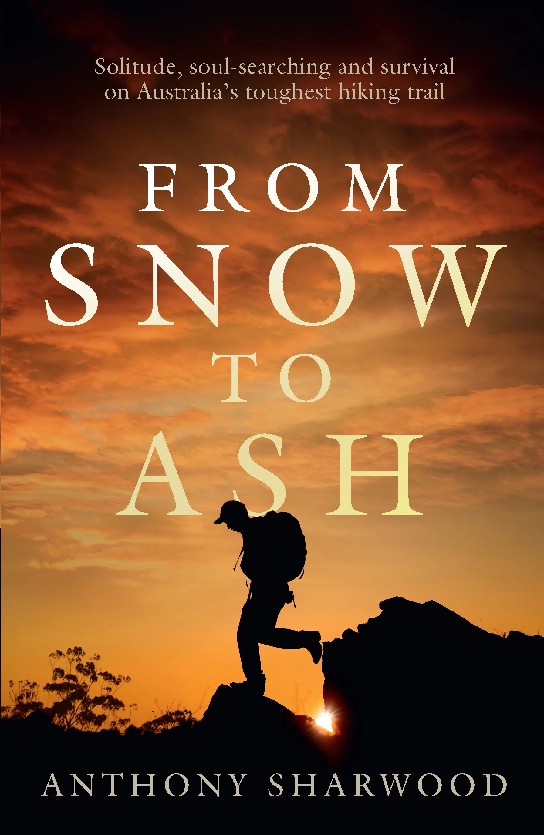 Book cover with a silhouette of a person climbing rocks against a sunset sky, with trees in the foreground and title text 'From Snow to Ash' by Anthony Sharwood.