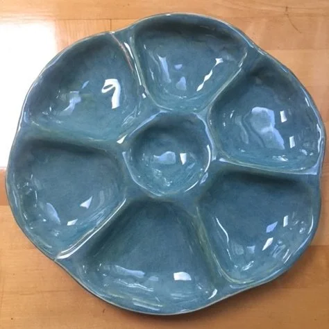 A blue, round, divided serving dish with five compartments, placed on a wooden surface.