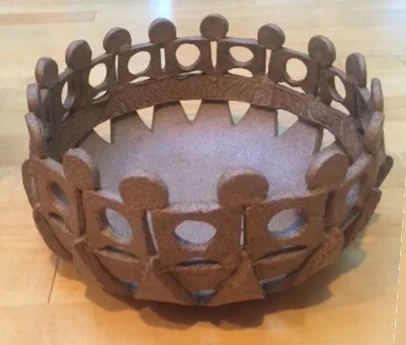 Wooden crown with circular ornaments and cut-out shapes, placed on a wooden surface.