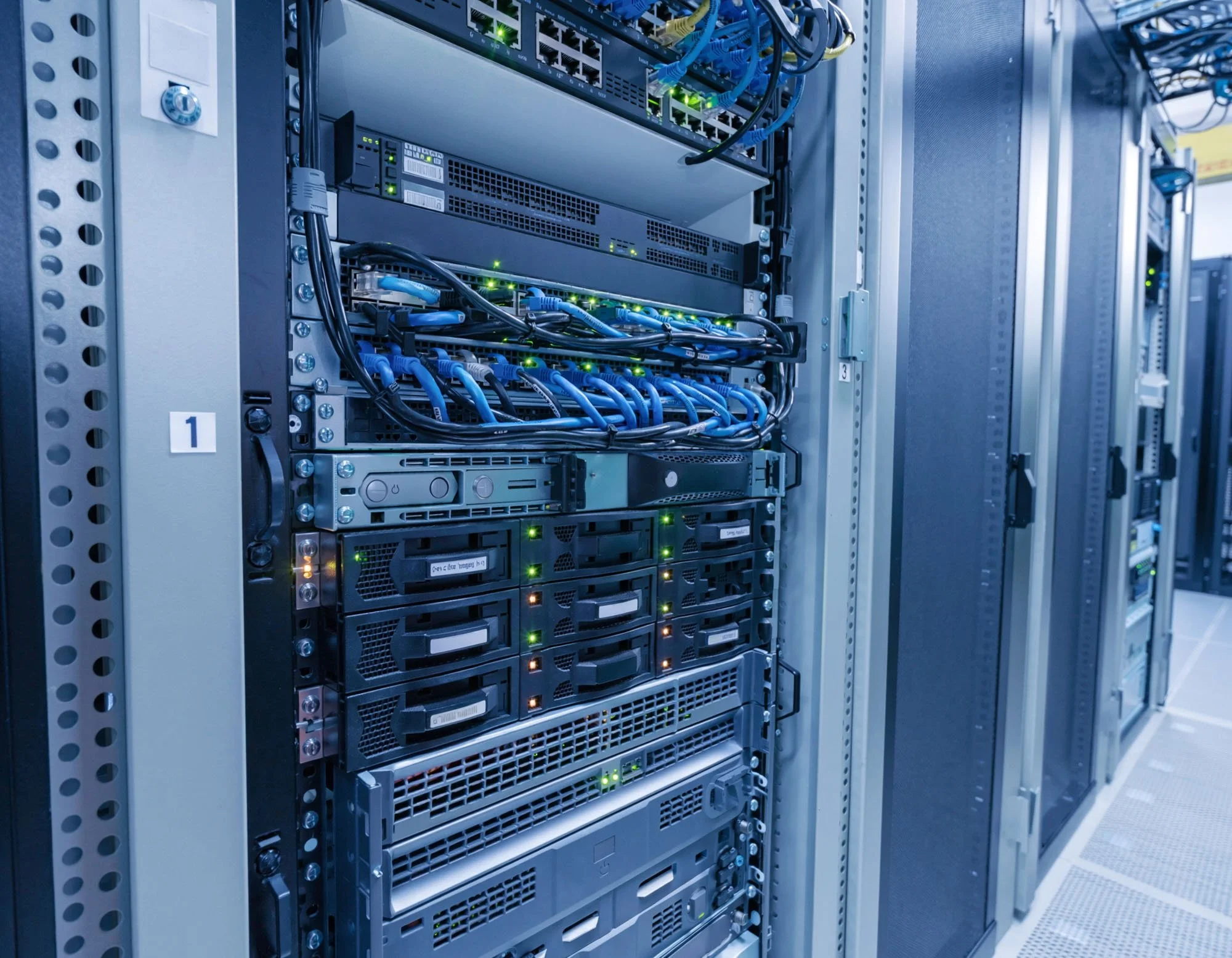 Data center server racks with networking equipment, cables, and blinking lights.