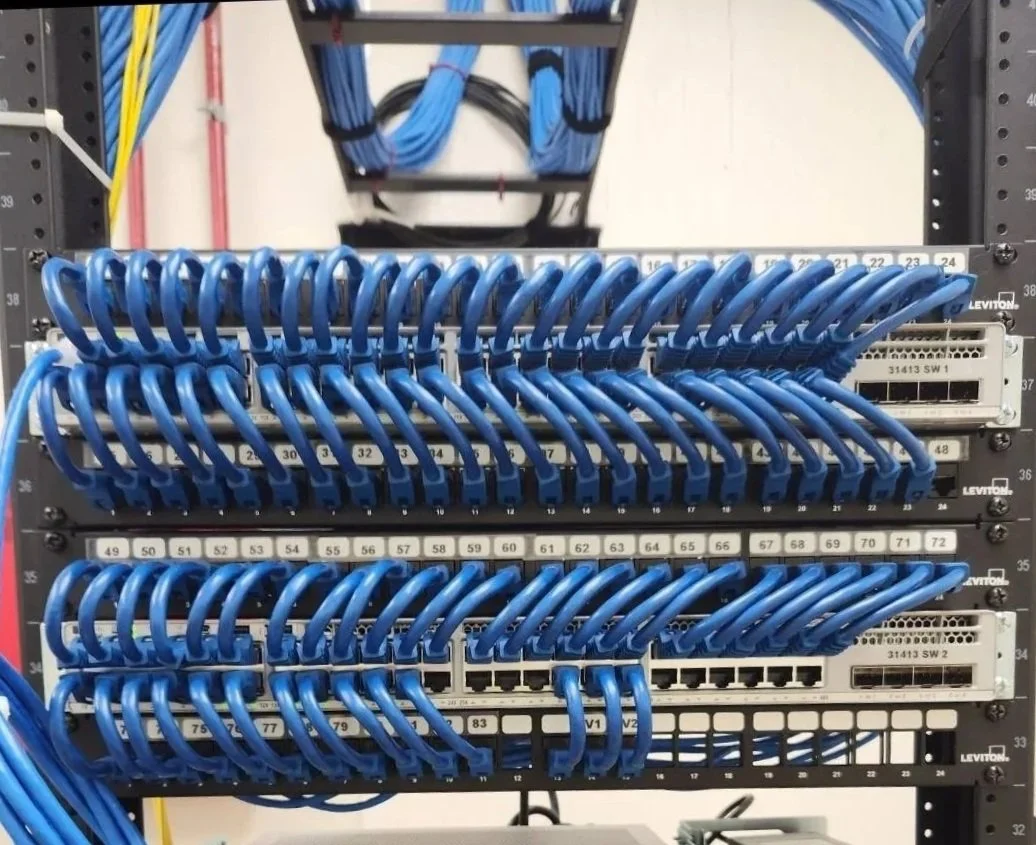 Network patch panel with organized blue ethernet cables connected to ports.
