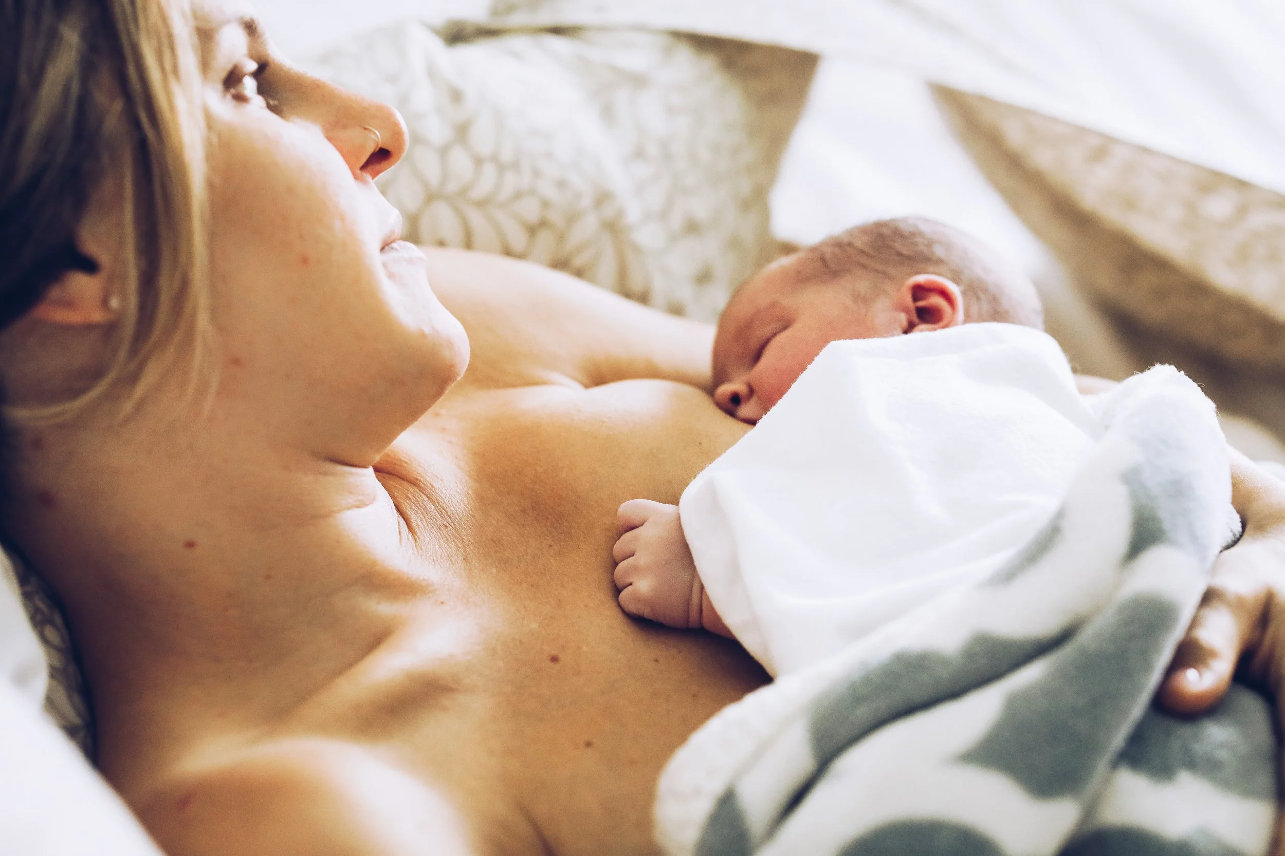 A woman breastfeeding her newborn baby in a cozy setting.
