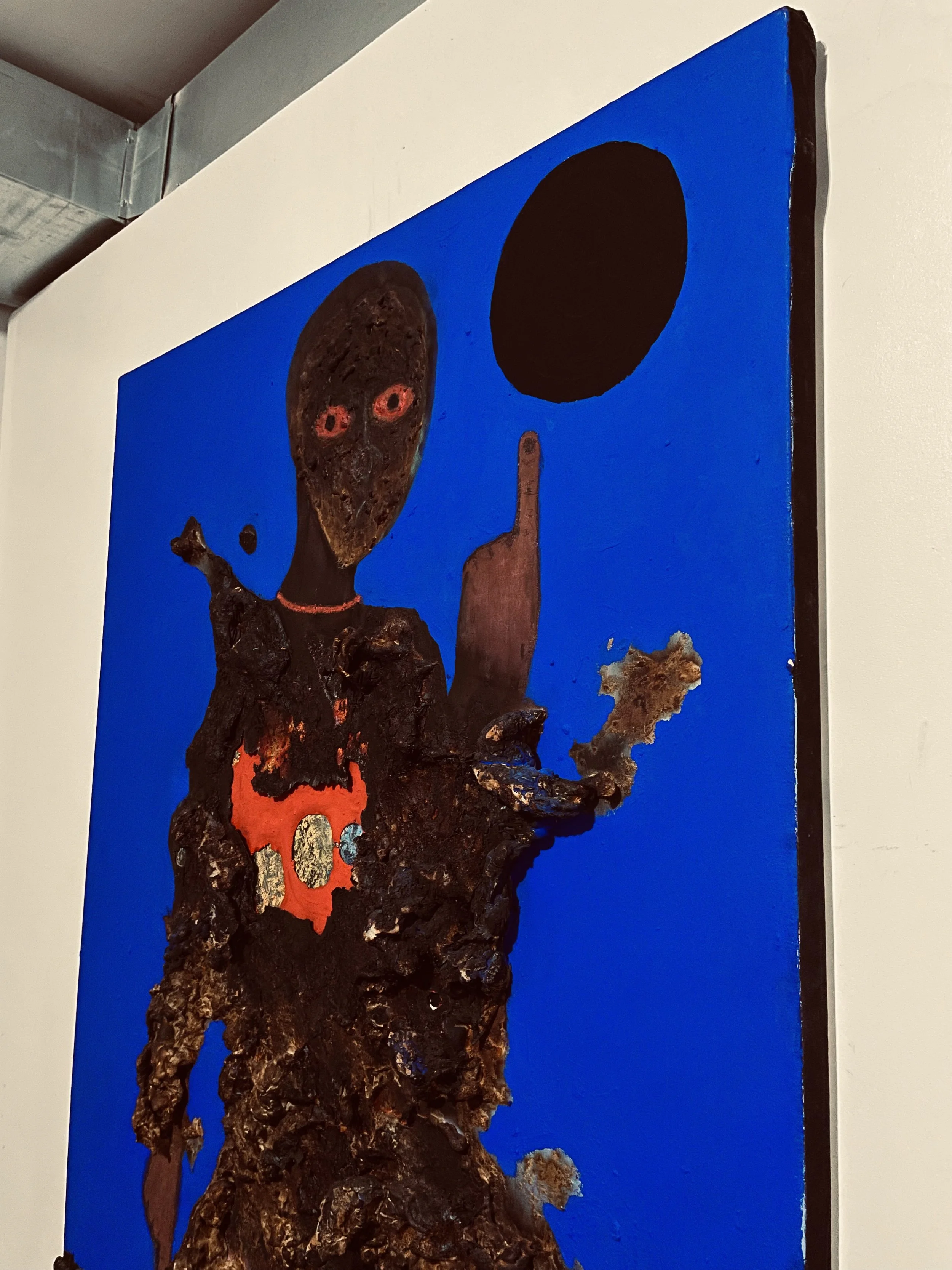 Contemporary artwork depicting a figure with an abstract face, a black circle above, and the figure's middle finger raised, set against a blue background.