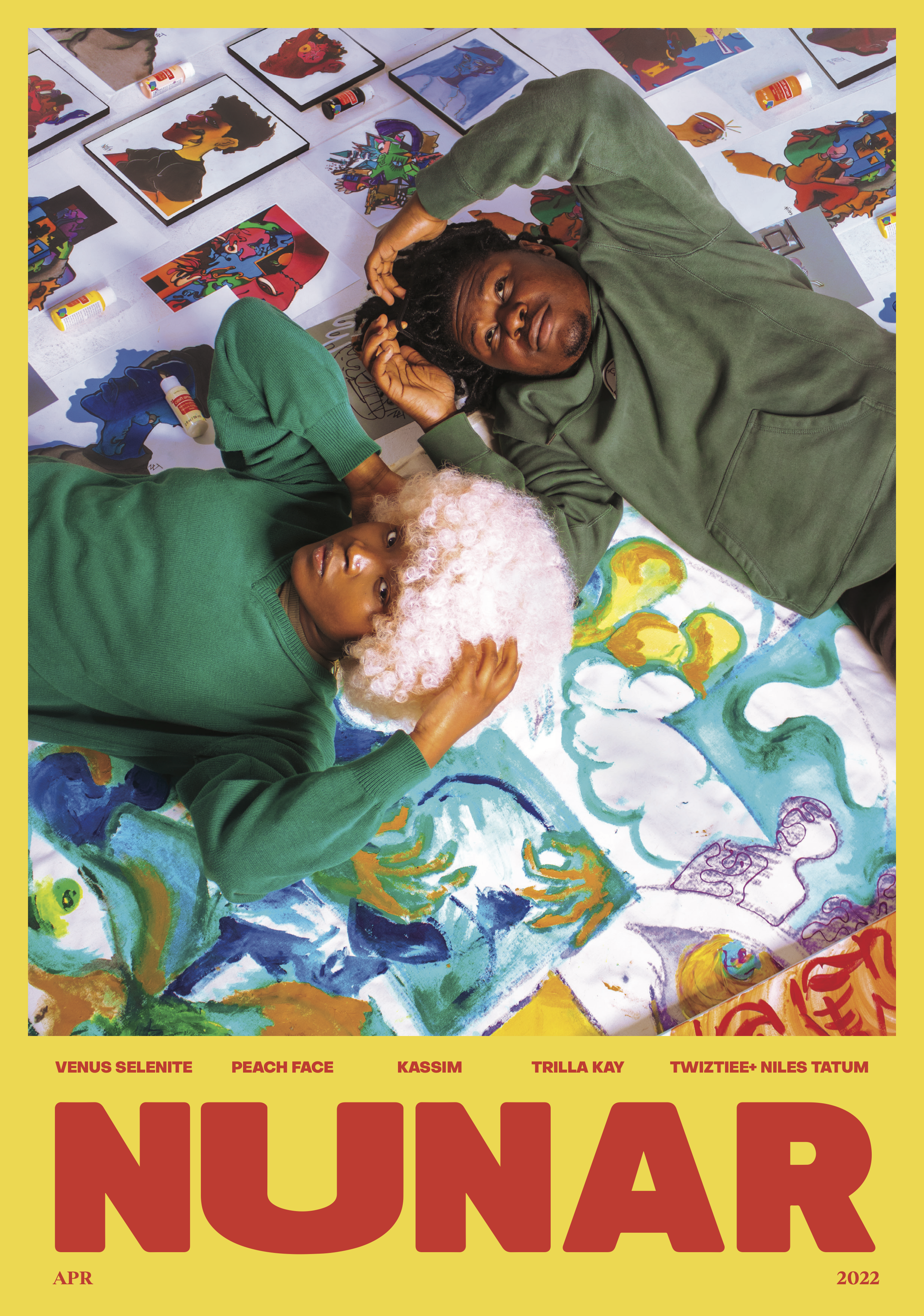 Two children lying on the floor amidst colorful artwork and supplies. One child has curly pink hair and is wearing a green sweater, while the other has dreadlocks and is wearing a green hoodie. They are surrounded by images of artwork, paint bottles, and markers.