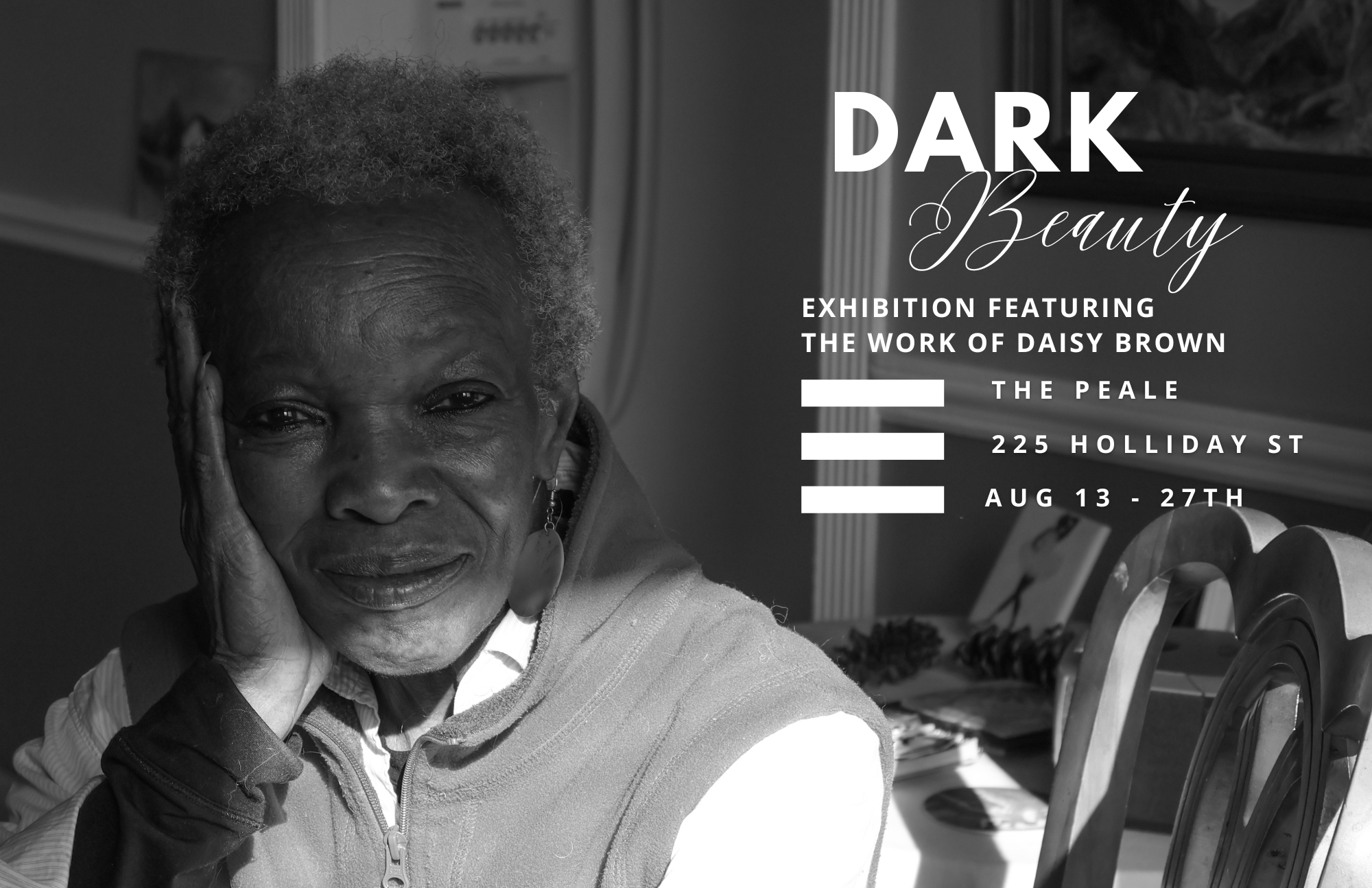 Black and white photograph of an elderly woman with gray curly hair, resting her face on her hand, smiling gently, sitting in a room with artwork and furniture. Overlaid text promotes an art exhibition titled "Dark Beauty" featuring the work of Daisy Brown, at The Peale, 225 Holliday St, from August 13 to 27.
