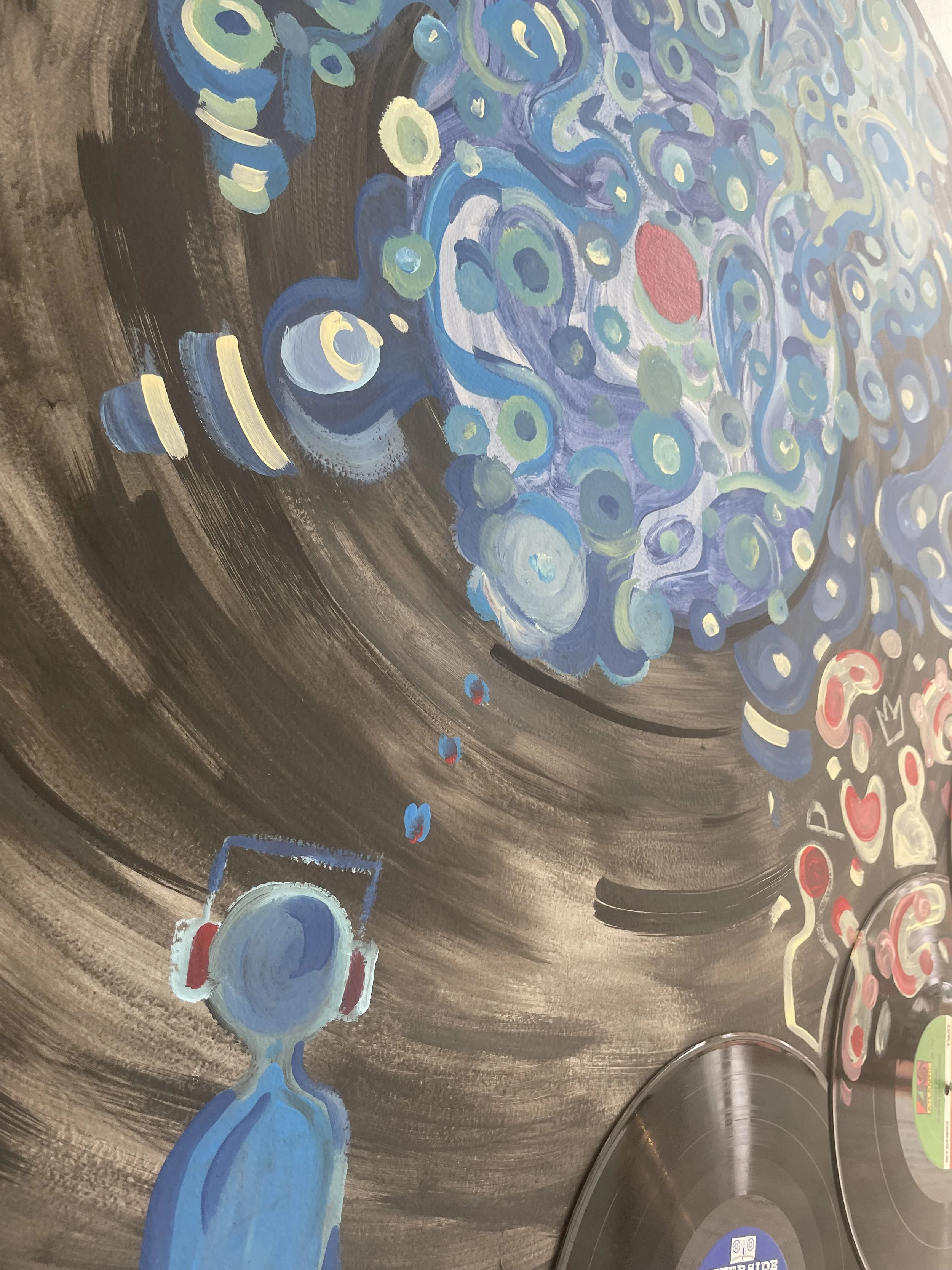 A colorful mural depicting a person wearing headphones in front of an abstract swirling design of blue, green, and red circular shapes.