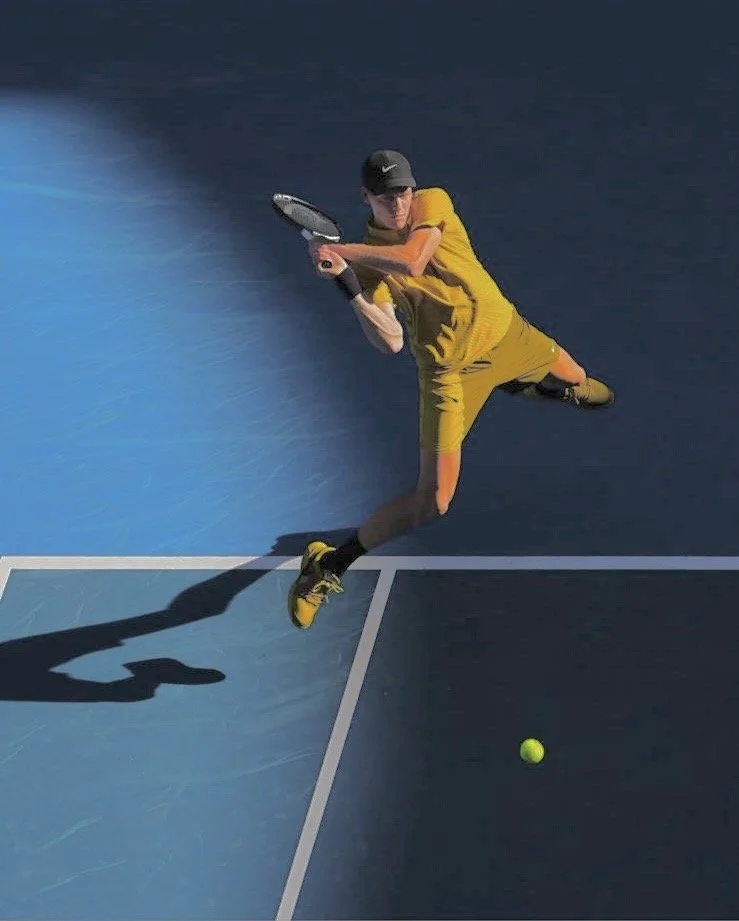 A young tennis player wearing a yellow shirt, matching yellow shorts, a black cap, and tennis shoes, playing on an indoor blue tennis court. The player is preparing to hit a tennis ball with a racket.