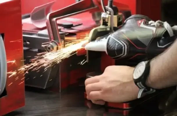 Person using a handheld power tool to cut metal, with sparks flying, in a workshop setting.
