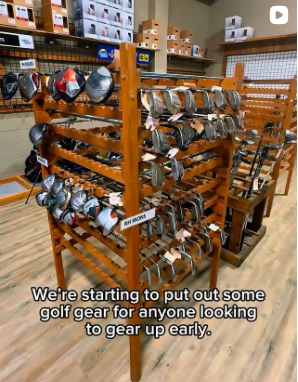 Wooden retail display shelf holding golf helmets and hats in a store.