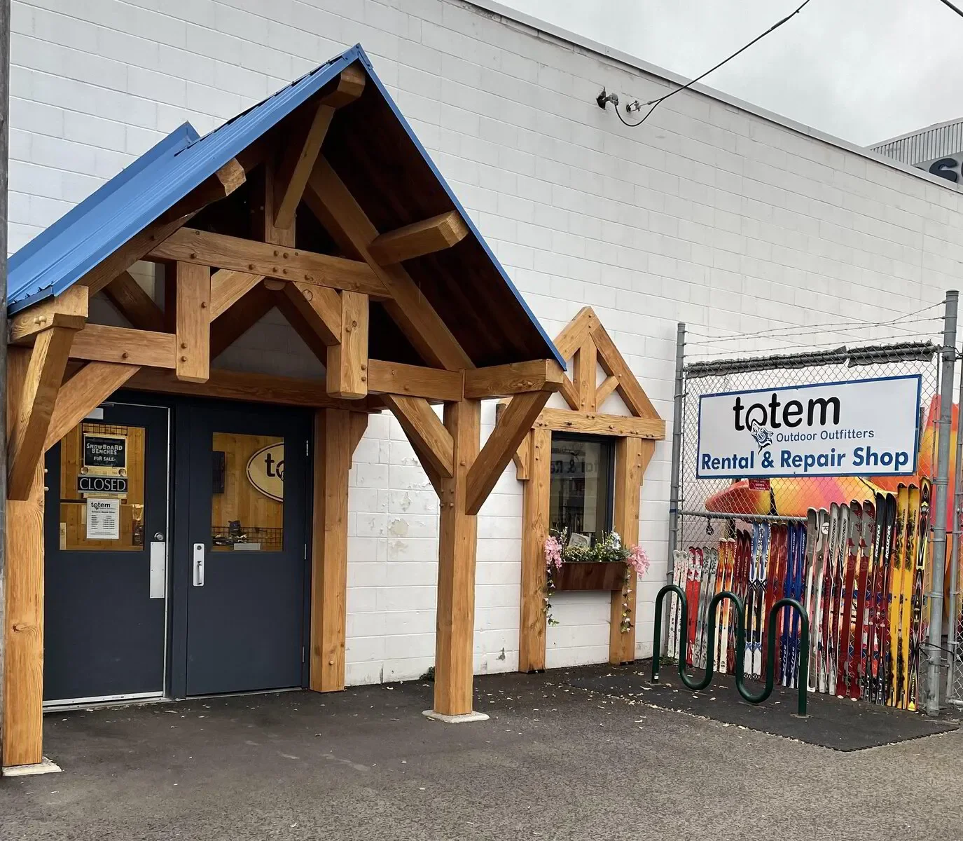 The repair shop entrance featuring a wheelchair accessible door. Skis of all sizes are lined up outside a sign that says: Rental & Repair Shop