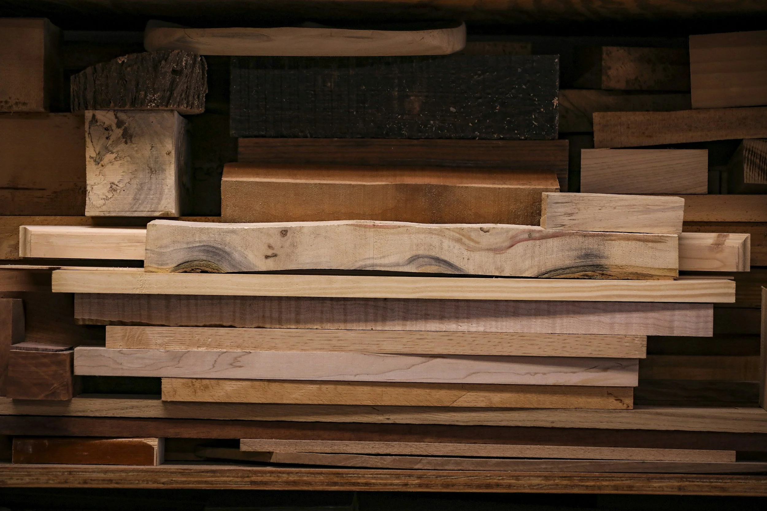A close-up view of various wooden planks and blocks arranged in an overlapping pattern, showcasing different wood textures and colors.