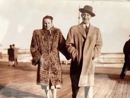 a black and white photo of a woman and man dressed up at a boardwalk