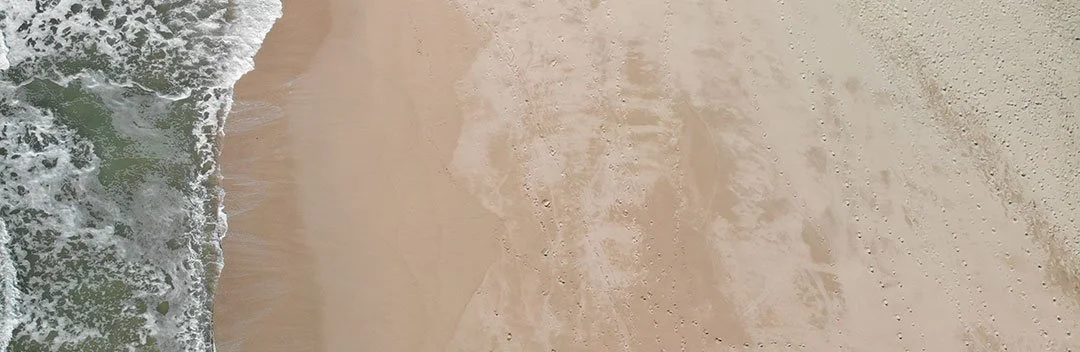 Close-up of sandy beach with gentle waves washing onto the shore