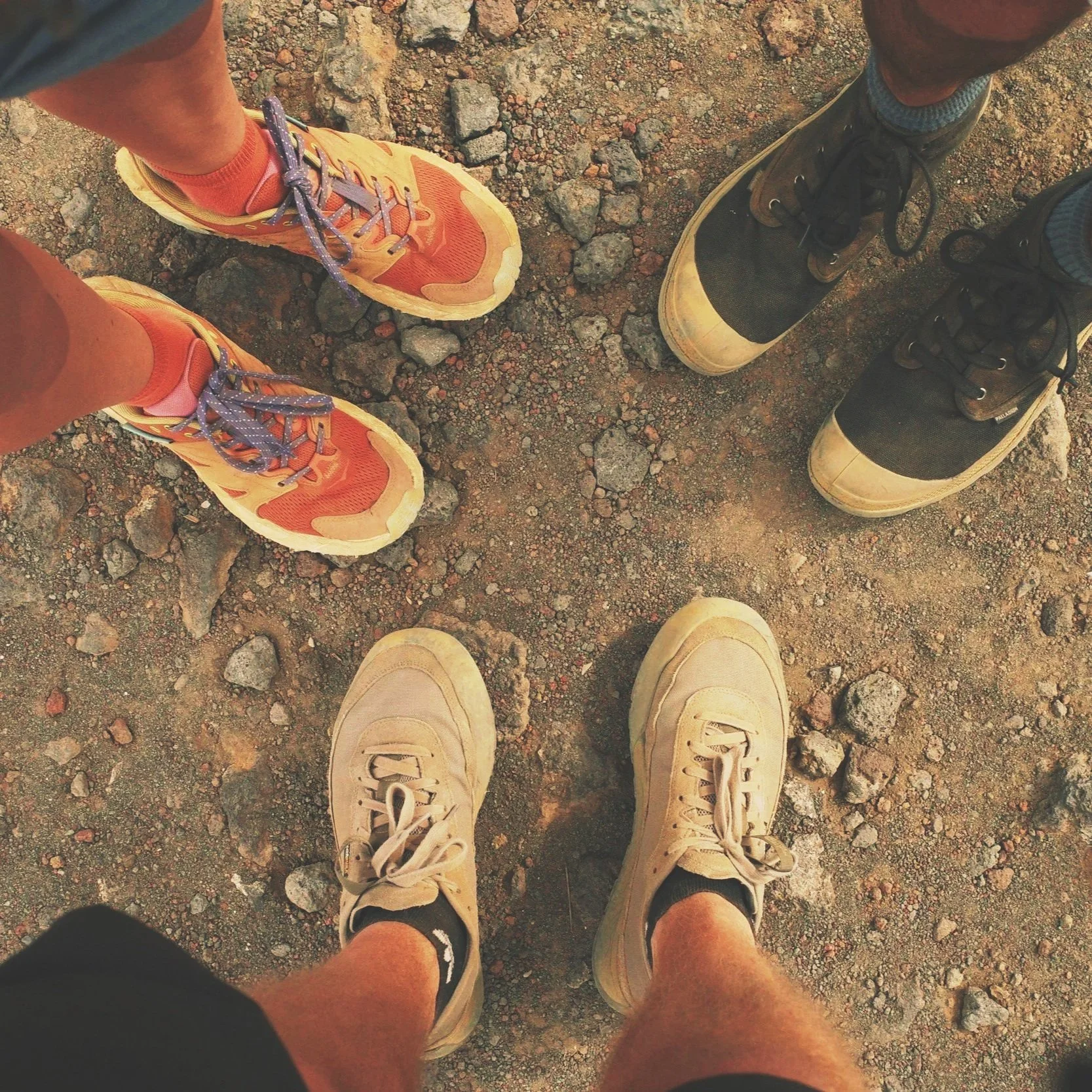 Four pairs of shoes on rocky, uneven ground, engaging in a small group exercise