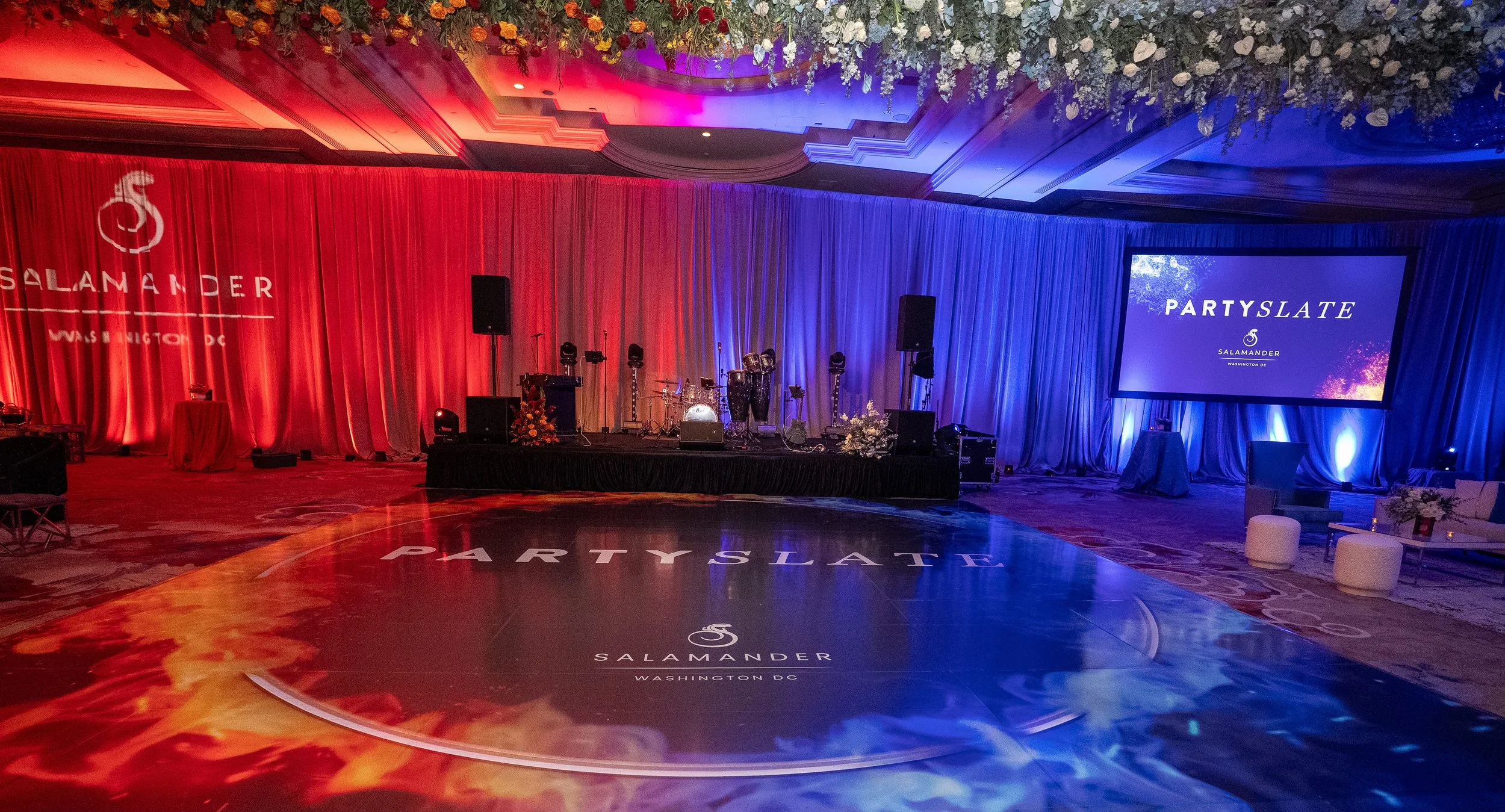 Ballroom event setup with dramatic red and blue split uplighting and projection screen by RDAV