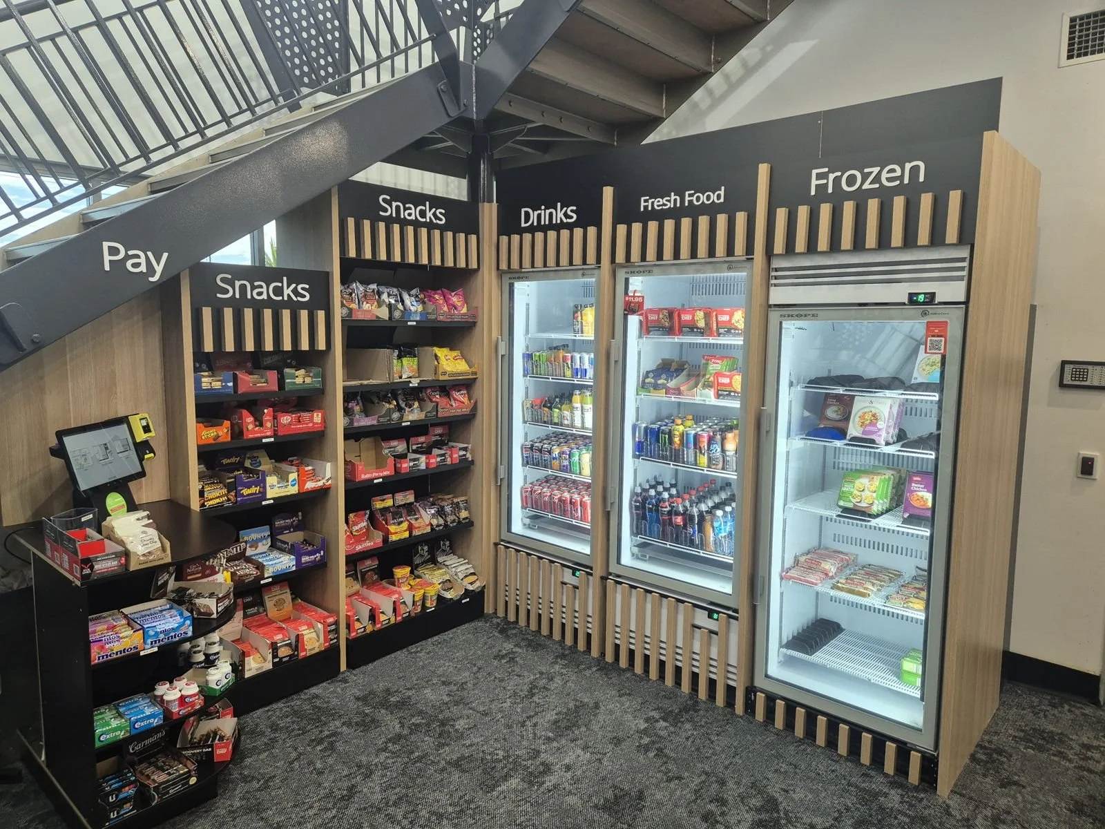 Snackaroo workplace micro market with snack shelving, drinks, fresh food and frozen fridges and a self-serve payment terminal