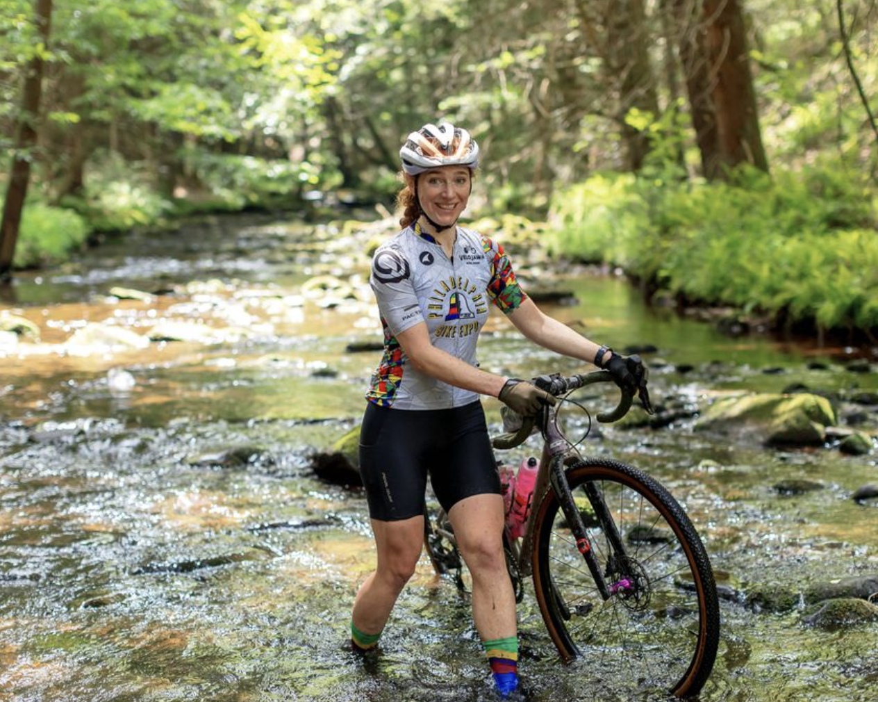 Lady smiling while walking thru ankle deep stream..
