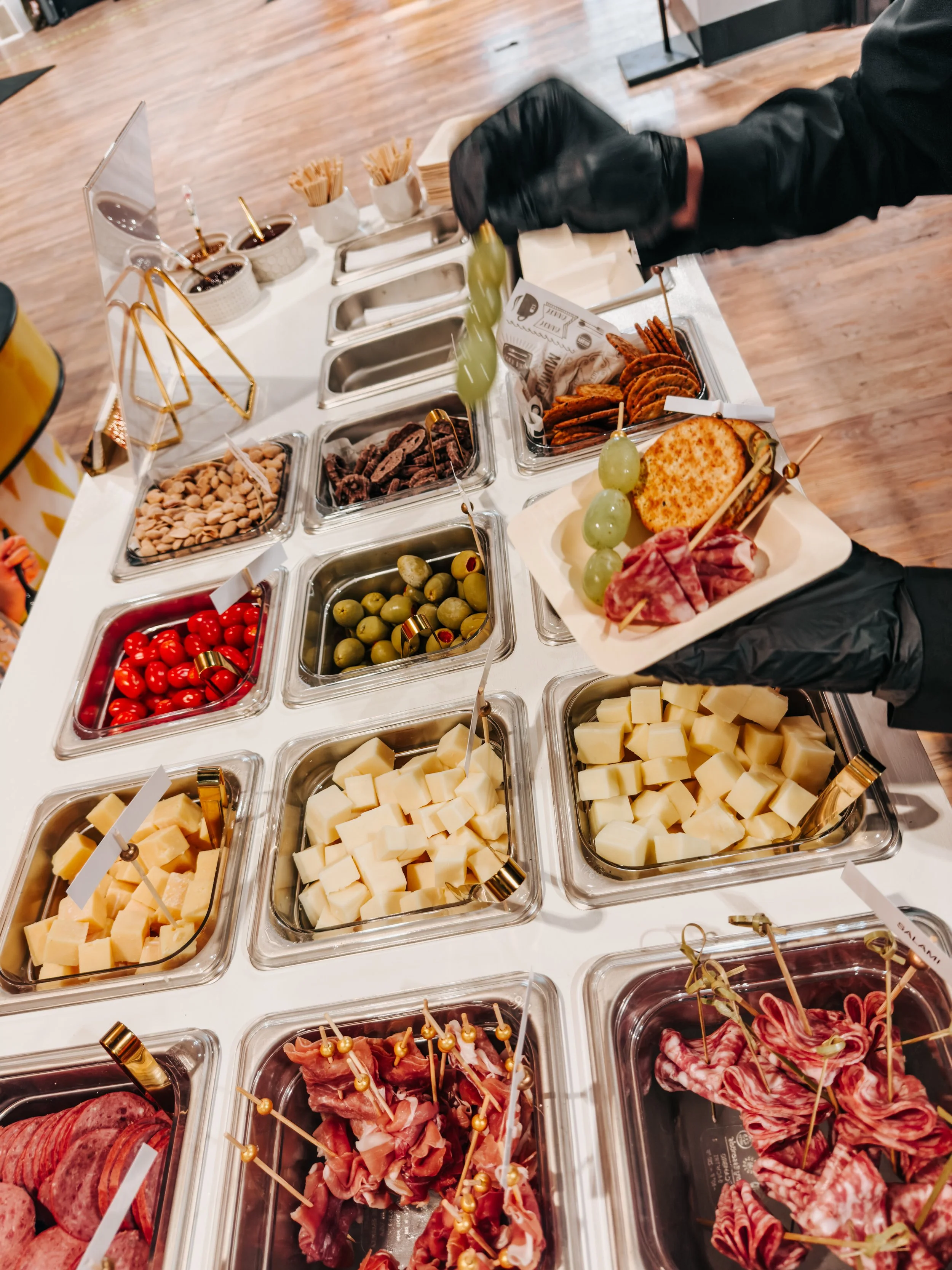 A breakfast or brunch station with various toppings and ingredients, labeled in French, in a wooden and white display with heart graphic and text 'Charcuterie D'Amour'.