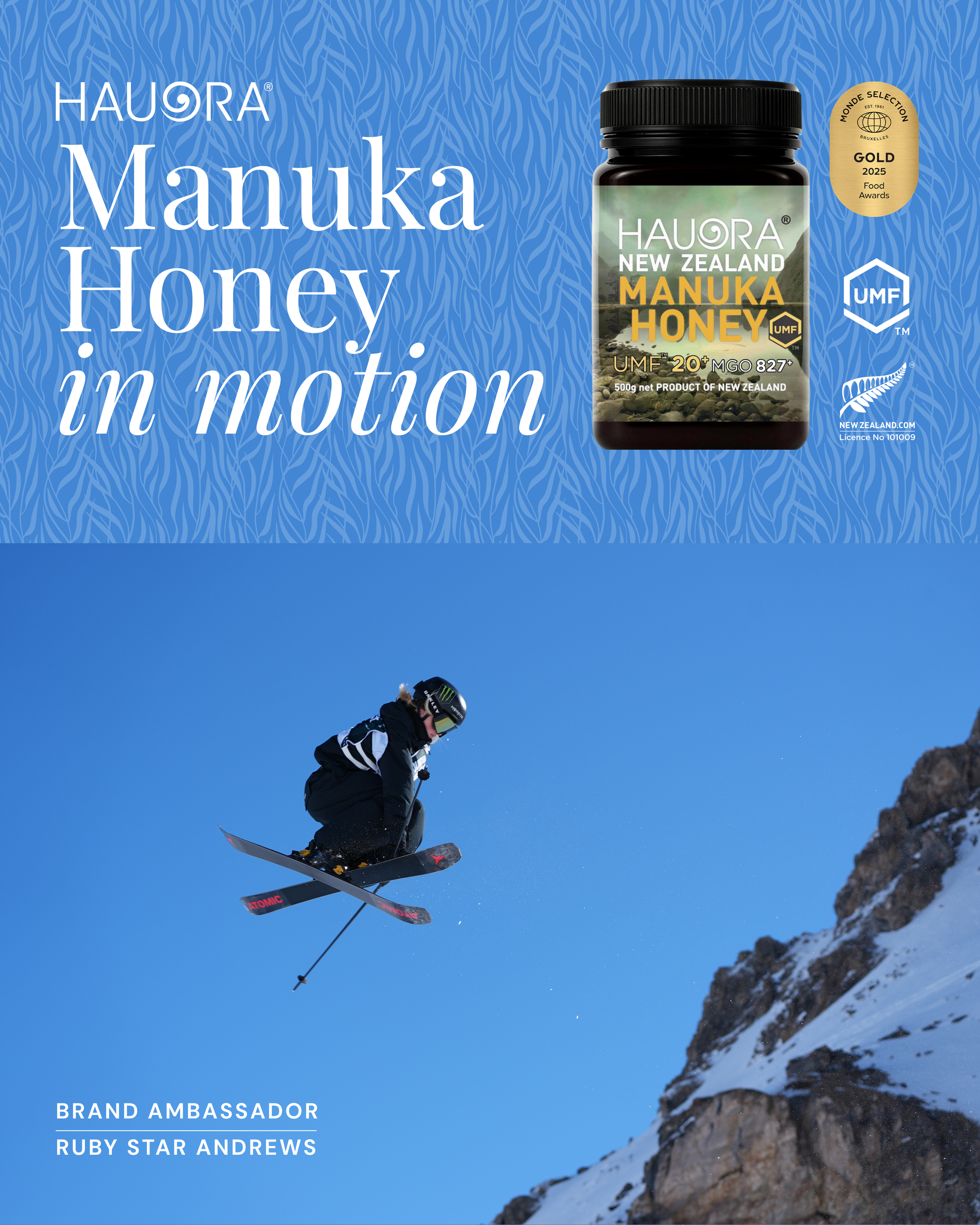 A person in winter gear snowboarding down a mountain slope with a bright blue sky in the background. There are rocks and snow on the mountainside.