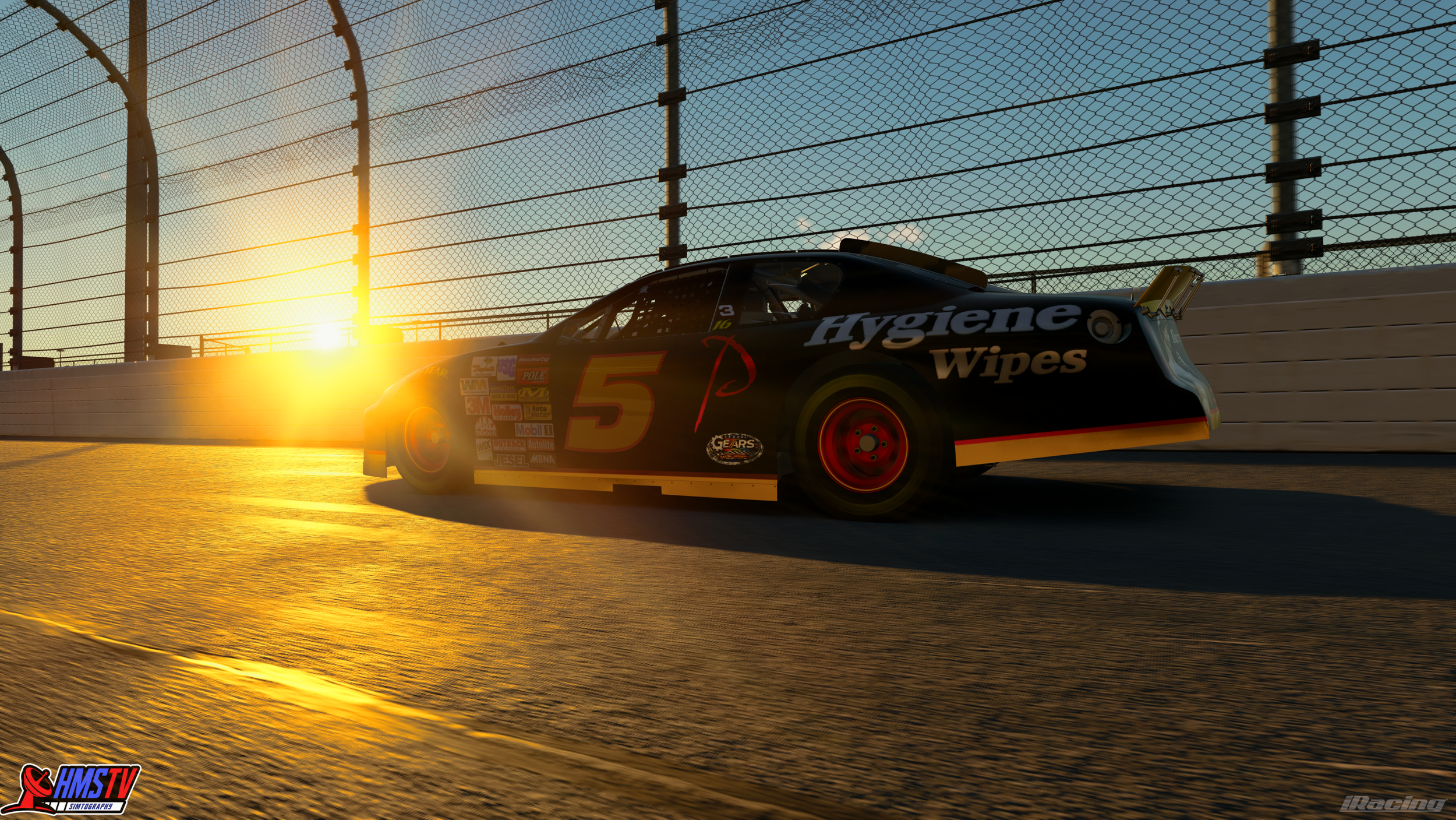 A black race car with the number 5 on the side, driven by a driver wearing a helmet, on a racing track at sunset, near a fence.