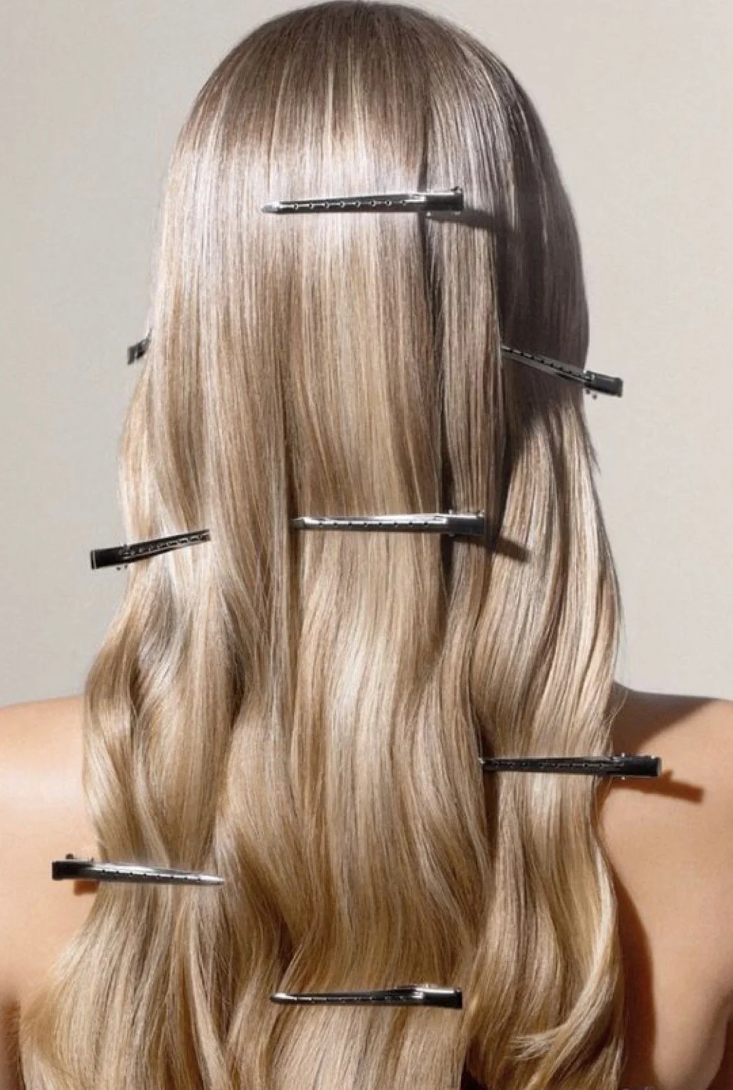Back of a person with long, wavy blonde hair clipped with black hair clips.