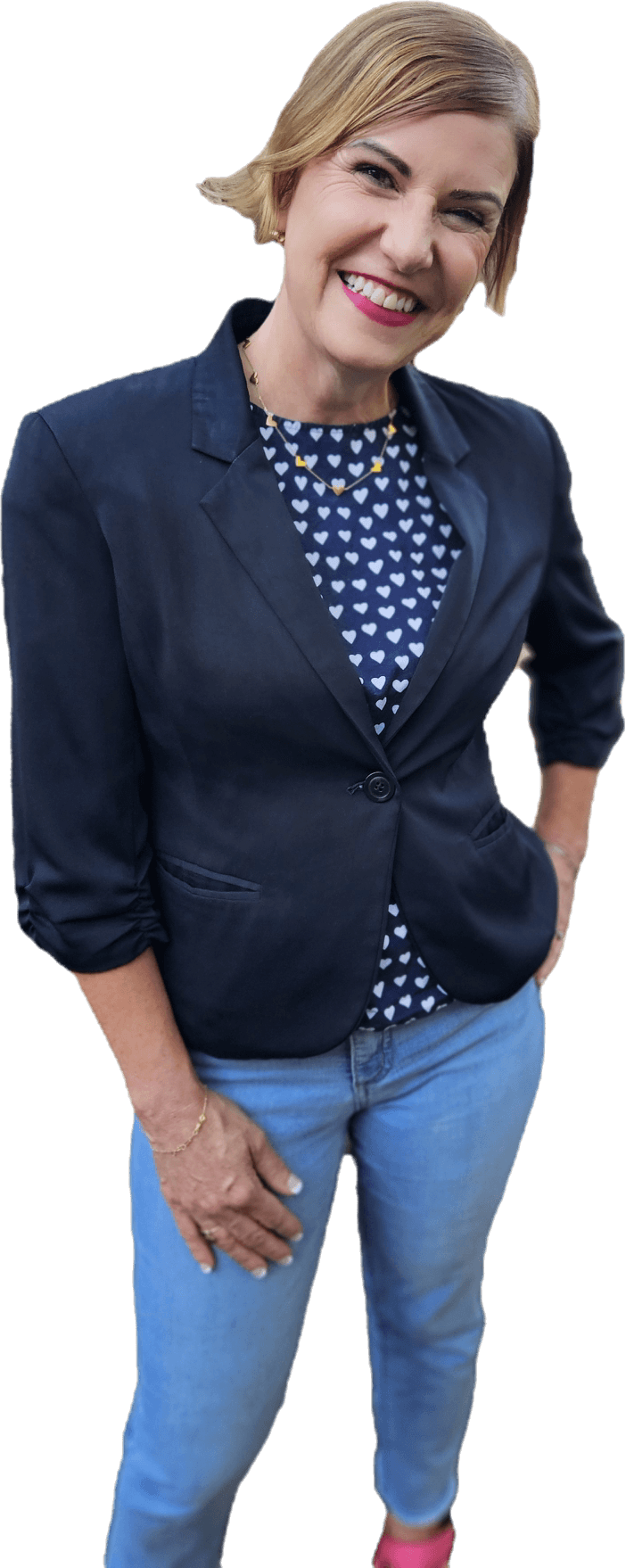 Rachel Muir smiles warmly, dressed in a navy blazer over a heart-patterned top, paired with light jeans and vibrant pink shoes, embodying the joy of nonprofit fundraising.