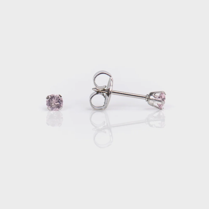A pair of pink gemstone stud earrings with a silver setting, one laying flat and the other with its post visible.
