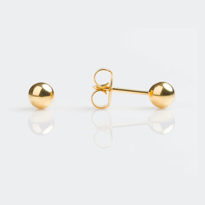 A pair of gold ball stud earrings, with one earring showing the back and post, and the other showing the front, on a white reflective surface.