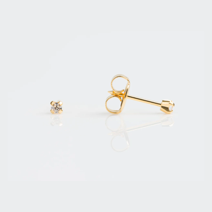 Close-up of a pair of gold stud earrings with clear gemstones on a white surface.