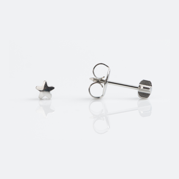 Small star-shaped silver earrings on a white reflective surface.