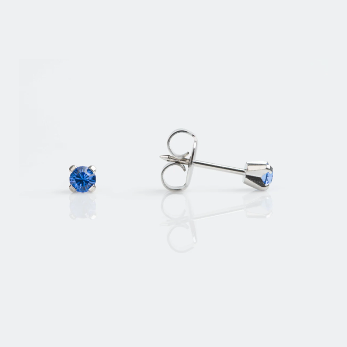 Silver earrings with blue gemstones on a white reflective surface