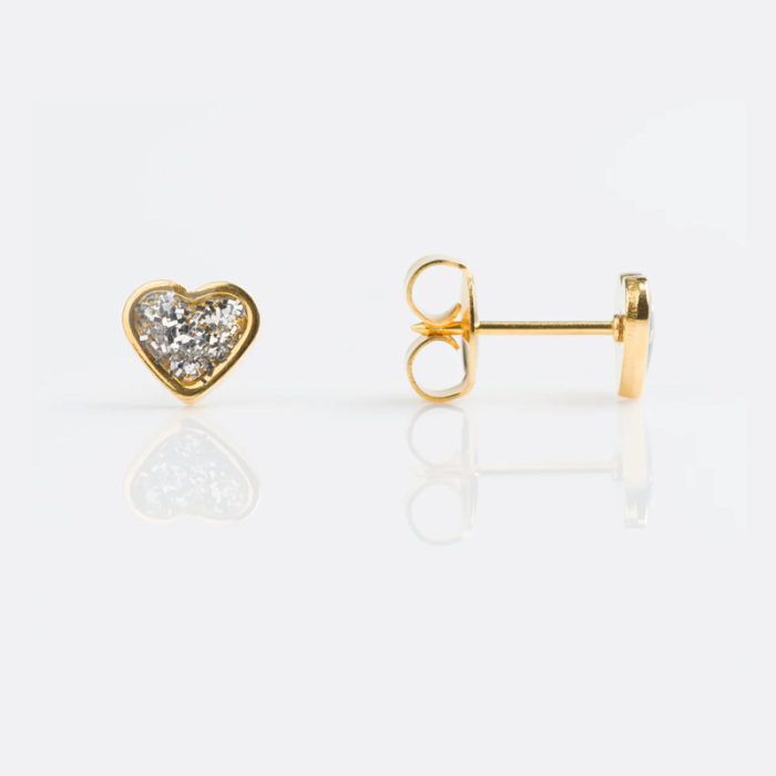 Gold heart-shaped stud earrings with embedded clear gemstones on a reflective white surface.
