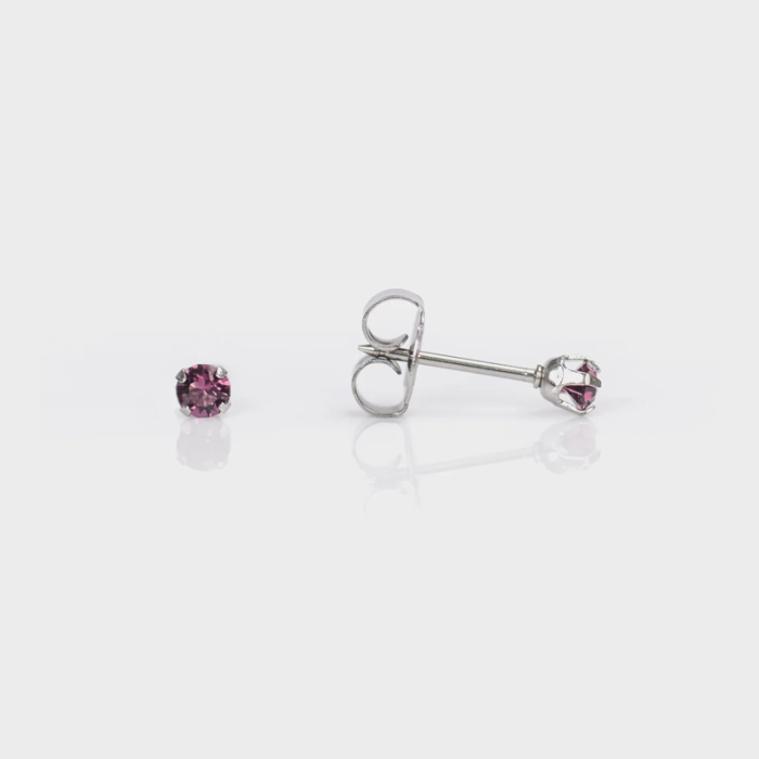 Pair of silver stud earrings with pink gemstones on white reflective surface.
