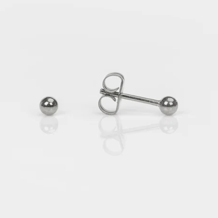 A pair of silver spherical stud earrings, one with its post and back visible, laid on a white surface.