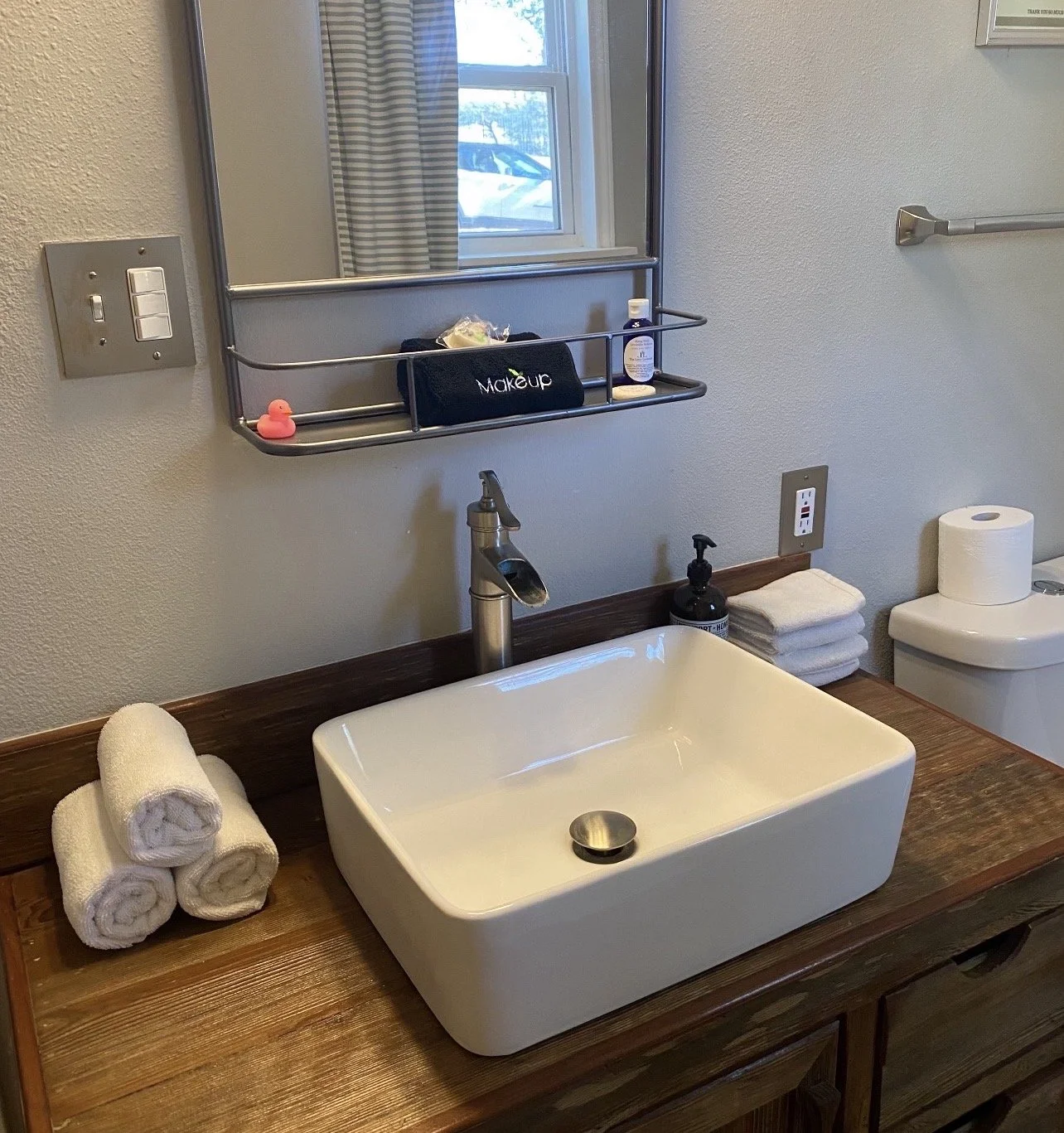 Professionally cleaned Airbnb bathroom vanity featuring rolled towels, guest amenity kit, and spotless surfaces.