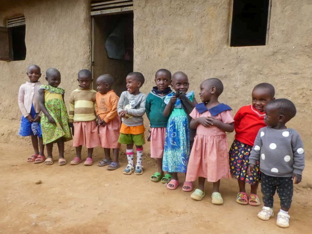 Ten little Batwa children standing in front of the Heart 2 Heart Primary School in Uganda, Africa