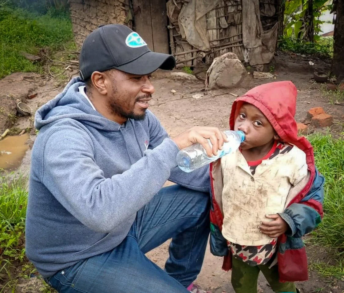 Richard giving a child a drink of water in Uganda, Africa