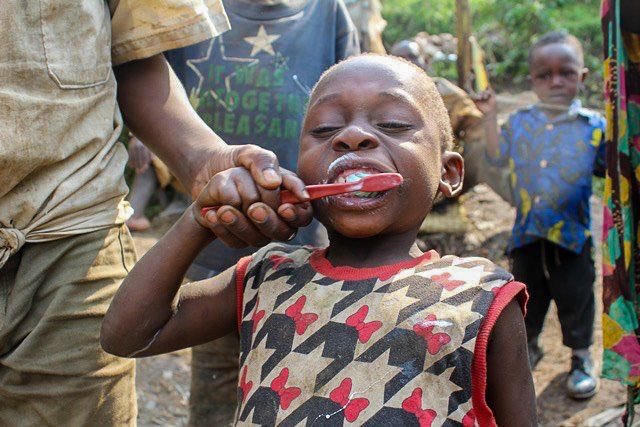 Batwa young boy brushing his teeth with a donated toothbrush from H2HIntl