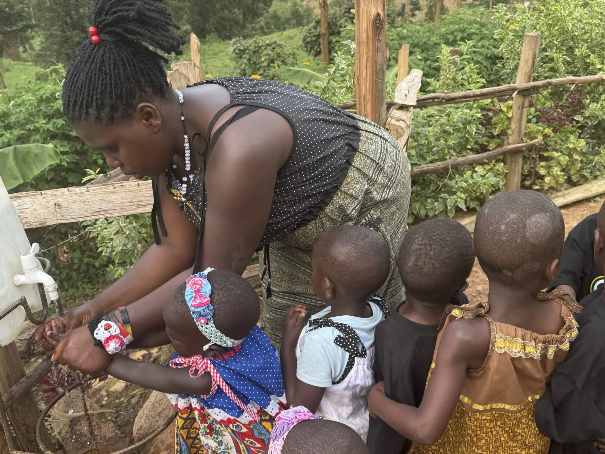 Teacher helping Batwa children wash their hands