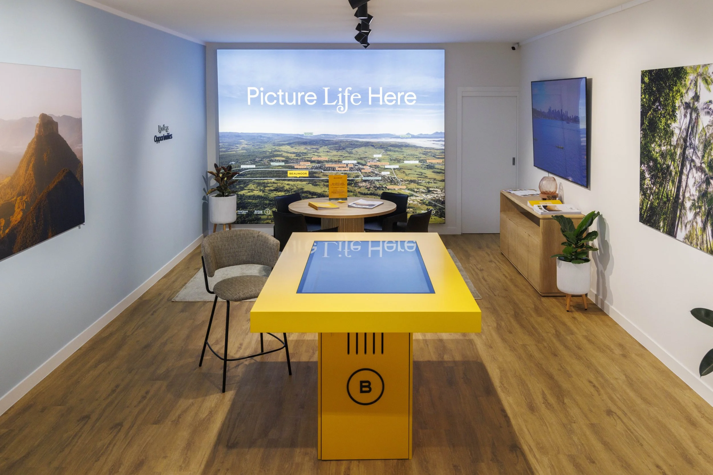 Modern commercial fitout featuring a branded display suite with custom joinery, interactive display table, and large-format wall graphics, designed to create an engaging customer experience in a premium sales environment.