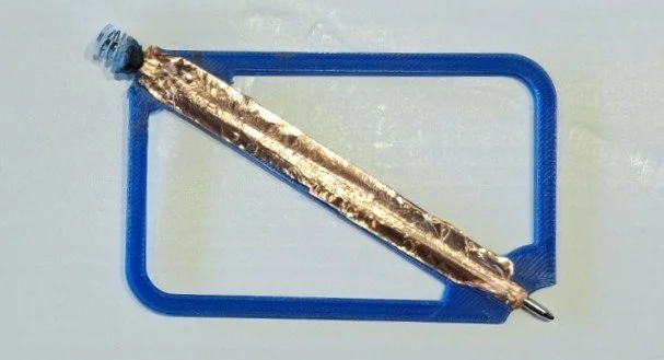 A ballpoint pen with a gold-colored body resting inside a blue square frame.