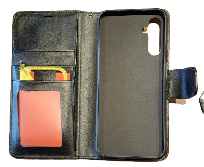 Open black leather wallet phone case with a phone holder and multiple card compartments, one containing a coral-colored card and a small yellow item.