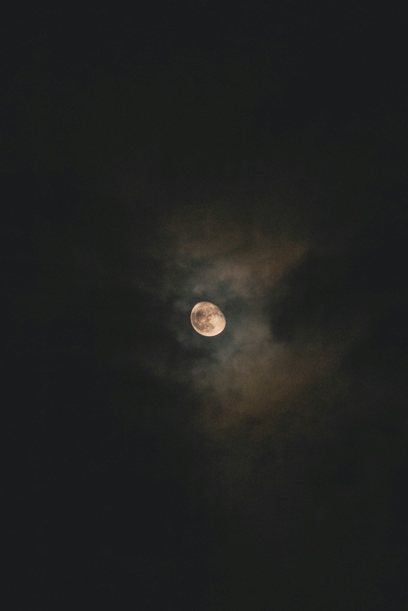 The moon shining through clouds in a night sky.