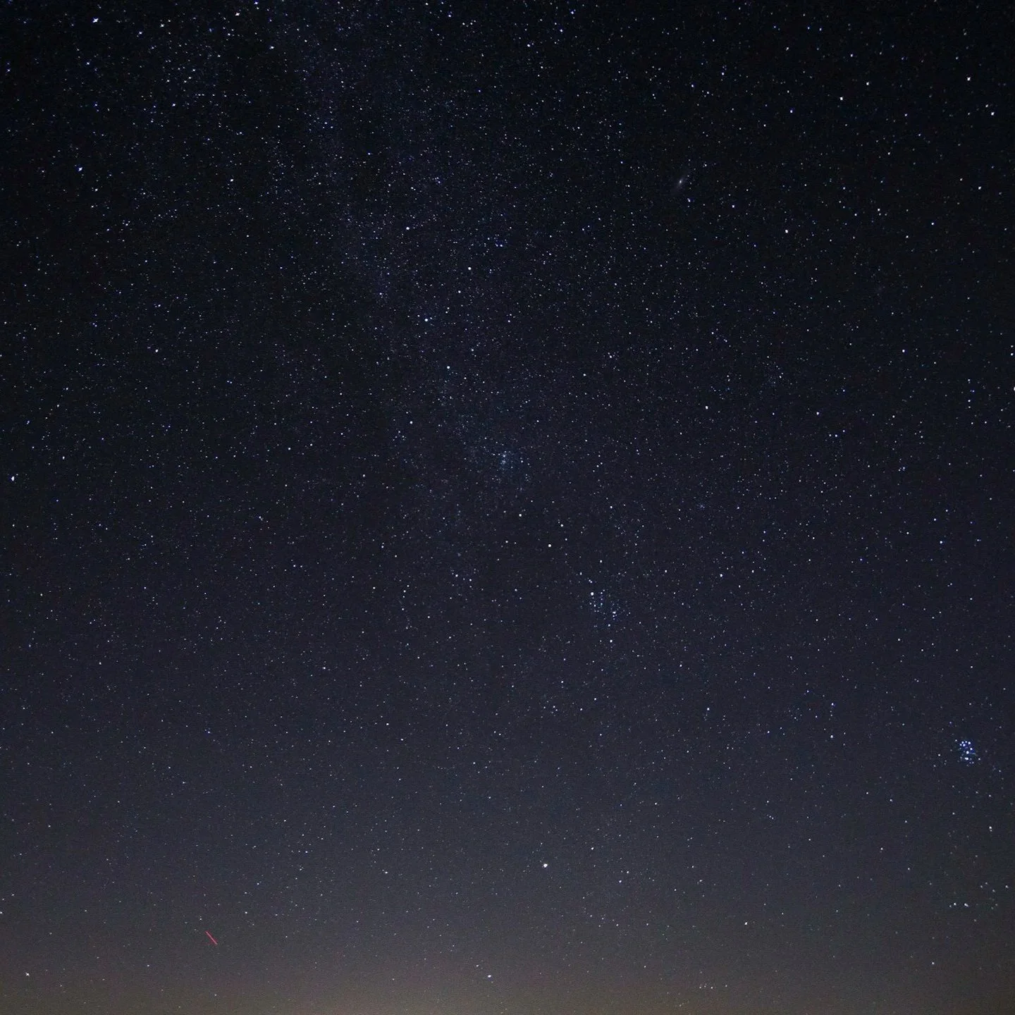 Clear night sky filled with numerous visible stars and a faint streak of a shooting star near the bottom left corner.
