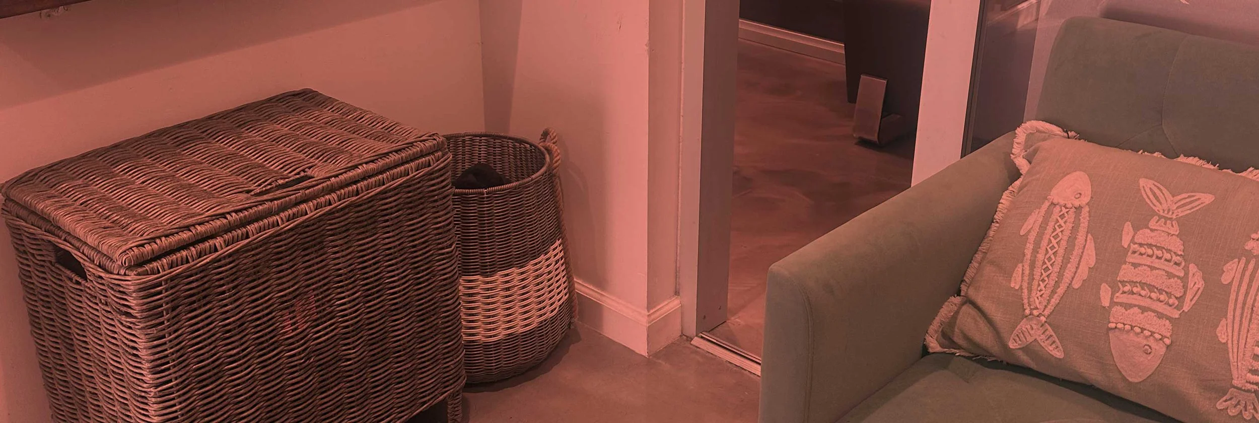 Hair Studio corner with wicker storage baskets and a beige couch with an ocean-themed pillow.