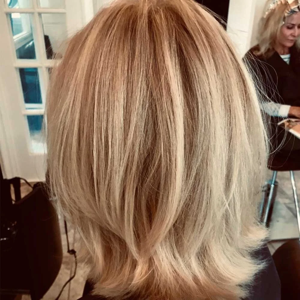 Back view of a woman with layered blonde hair.
