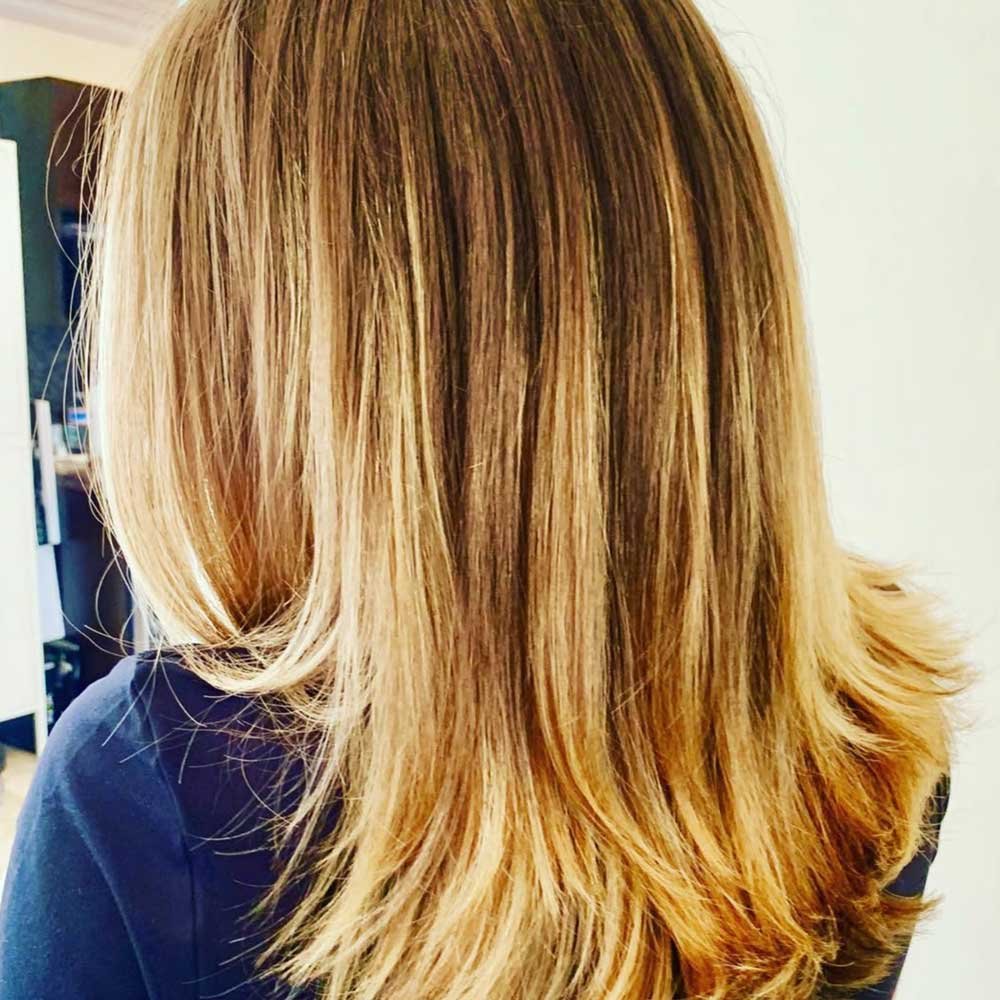 Back of a woman's head showing shoulder-length blonde hair with subtle highlights.