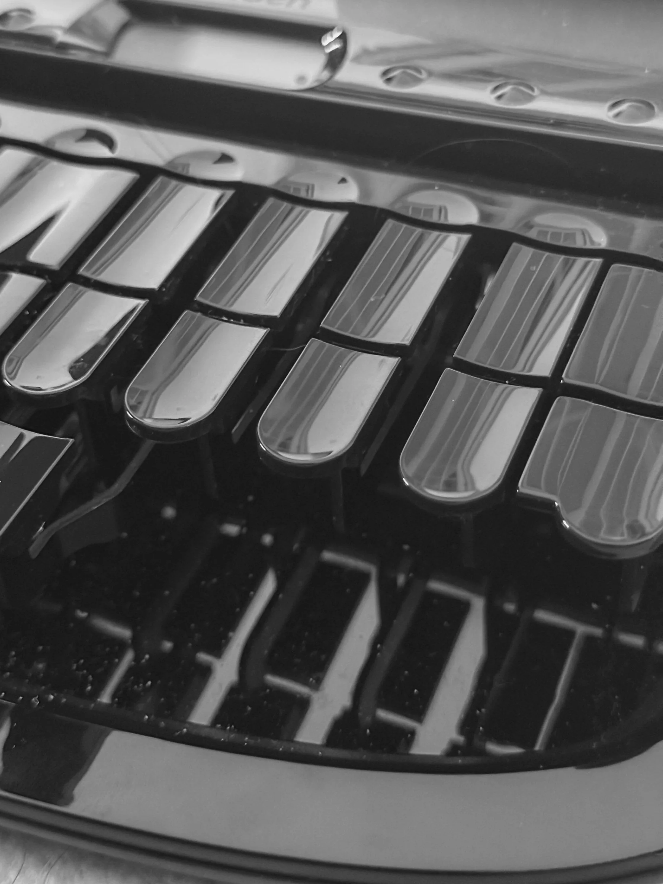 Close-up of a stenography keyboard in black and white, showing the detailed design of the keys with reflections on the surface.