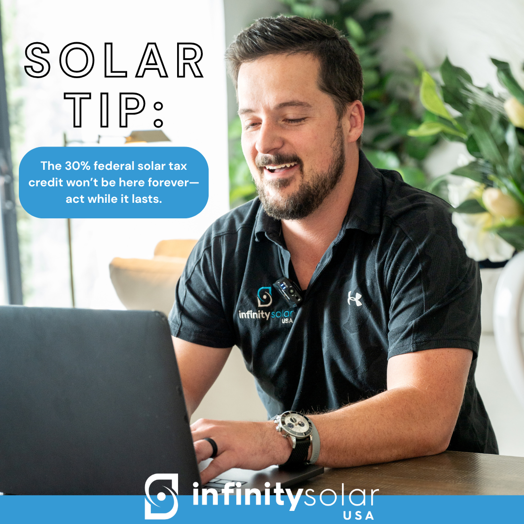 A man with a beard at a desk using a laptop, wearing a black polo shirt with the 'Infinity Solar USA' logo and a wristwatch, with plants in the background. Text overlay sharing a solar energy tip.